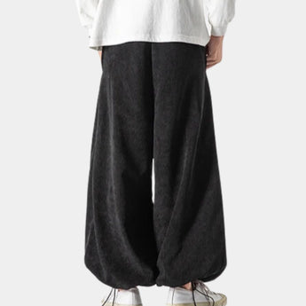 Black unisex wide-leg palazzo trousers with a high waist, featuring a modern design suitable for both formal and casual settings.