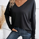 A woman wearing a black V-neck long sleeve blouse, styled casually with jeans. The blouse is lightweight and fits comfortably, perfect for everyday wear.