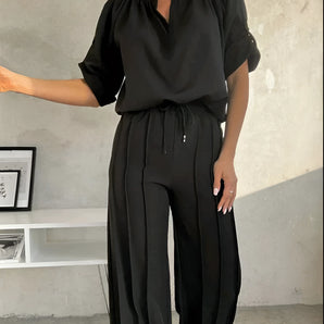 Black V-neck women's jumpsuit, lightweight with drawstring waist, plus size 4XL, modeled by woman.