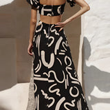Black and white abstract two-piece dress featuring an off-shoulder top and palazzo pants, showcasing fashion-forward design with a focus on the shoulder and waist areas.