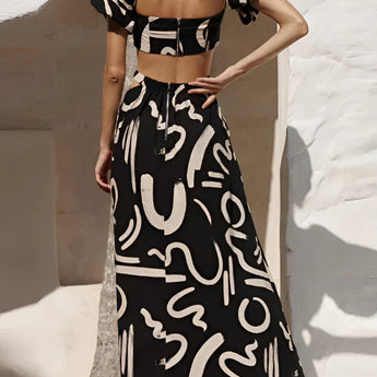 Black and white abstract two-piece dress featuring an off-shoulder top and palazzo pants, showcasing fashion-forward design with a focus on the shoulder and waist areas.