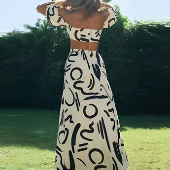 Black and white abstract two-piece dress featuring an off-shoulder top and palazzo pants, modeled outdoors with a natural background.