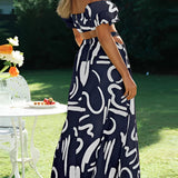 
A black and white abstract two-piece dress featuring an off-shoulder top paired with palazzo pants, worn by a model with long hair standing outdoors in a grassy area.