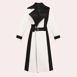 A black and white belted trench coat featuring a stylish collar and long sleeves. The coat has a chic, monochrome design suitable for formal events, demonstrating a classic and elegant outerwear style.