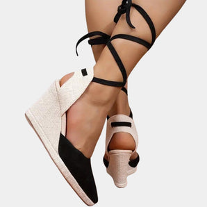 Black and white lace-up open toe espadrilles worn by a woman during summer, showcasing the footwear from a side angle with a focus on the shoe design and lace detailing.