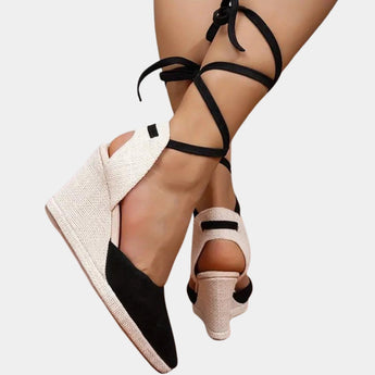 Black and white lace-up open toe espadrilles worn by a woman during summer, showcasing the footwear from a side angle with a focus on the shoe design and lace detailing.