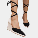 Black and white lace-up open toe espadrilles worn by a woman, showcasing the summer sandal design on her feet and legs.