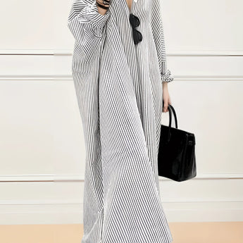 
A long sleeve maxi dress with black and white stripes, featuring a light gray tone. The dress is styled for breezy beachwear, showcasing a relaxed, flowing design with emphasis on shoulder and waist elements.