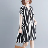 Black and white striped midi dress with short sleeves and button front, worn by a person showing their arm and shoulder.