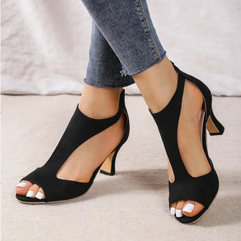 
A pair of black women's slingback stiletto peep-toe heels, styled for formal occasions. The image captures the sleek design of the heel, showcasing the elegant peep-toe front and the slender stiletto heel. The shoe is paired with a knee-length electric blue dress, emphasizing the sophisticated look.