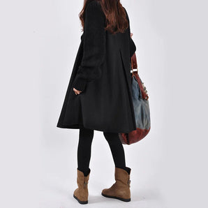 
A fashionable black wool coat and oversized cardigan designed for women's winter wear, featuring a knee-length cut, structured collar, and tailored sleeves. The coat embodies a trendy blend of a trench coat and blazer style, modeled by a fashion model.