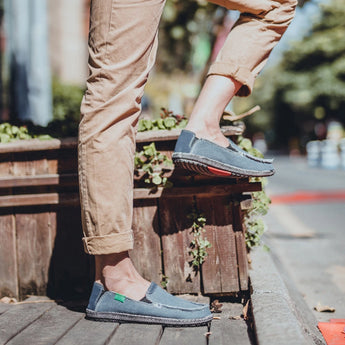 Black woven loafers designed as breathable and lightweight slip-on shoes, shown in a standing position on a wooden surface.