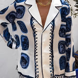 Blue satin pajama set featuring a luxurious designer style, with a white and blue color palette, long sleeves, and a collared neckline.