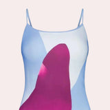 A woman wearing a blue floral maxi dress with spaghetti straps, suitable for beachwear or summer outings. The dress flows elegantly down to the ankles, showcasing a relaxed, casual style.