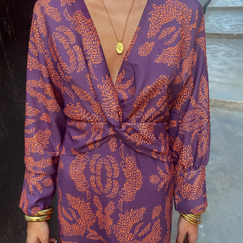 A woman wearing a blue floral midi dress with a V-neck and long sleeves, ideal for fall fashion and evening wear.
