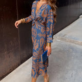 Woman wearing a blue floral midi dress with a V-neck and long sleeves, styled for fall fashion and eveningwear, available in 3XL size.