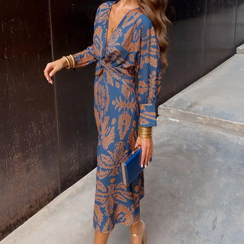 Woman wearing a blue floral midi dress with a V-neck and long sleeves, styled for fall fashion and eveningwear, available in 3XL size.