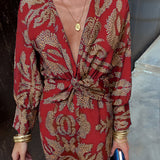 A woman wearing a blue floral midi dress with a V-neck, long sleeves, and a fitted waist, suitable for fall evening events.