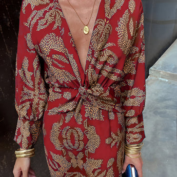 A woman wearing a blue floral midi dress with a V-neck, long sleeves, and a fitted waist, suitable for fall evening events.