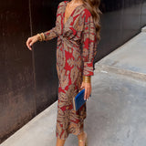Woman wearing a blue floral midi dress with a V-neck and long sleeves, suitable for fall fashion and evening events.