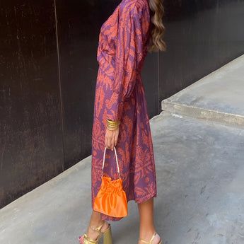 Woman wearing a blue floral midi dress with a V-neck and long sleeves, showcasing fall fashion suitable for evening wear. The dress highlights her shoulders, waist, and knees, as she stands in a runway pose.