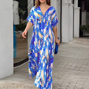 Blue floral V-neck maxi dress in size XL, featuring long sleeves, a cinched waist, and elegant resort wear design. The dress is styled with vibrant blue hues and floral patterns, perfect for summer outings and vacations.