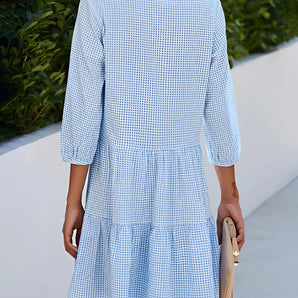 Blue gingham knee-length dress with a ruffled hem, ideal for lightweight summer wear.