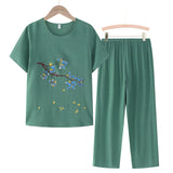 A women's green casual summer pants set featuring a blue linen top with floral embroidery, displayed on a clothes hanger.