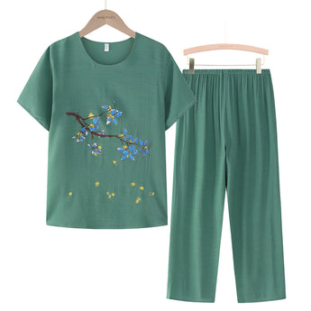 A women's green casual summer pants set featuring a blue linen top with floral embroidery, displayed on a clothes hanger.
