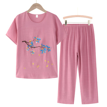 Light pink women's casual summer pants set featuring a blue linen top with floral embroidery and matching blouse on a clothes hanger.