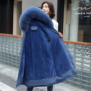 
A woman wearing a blue oversized faux fur hooded coat, showcasing luxurious winter outerwear with a focus on comfort and style. The coat features long sleeves and a plush texture, providing warmth and elegance.