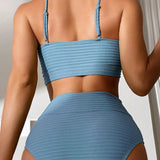 Blue ribbed bikini top with a twisted front design and adjustable straps, modeled on a person wearing matching blue shorts, showcasing the summer swimwear's fit around the shoulders, neck, and stomach.