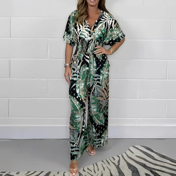 Elegant dark green tropical leaf print maxi dress with a flattering V-neckline, designed for summer wear. The dress features long sleeves and a fitted waist, with a stylish pattern that adds to its fashionable appeal.