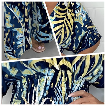 Blue tropical leaf print maxi dress with an elegant V-neck design, featuring short sleeves and flowing fabric in various shades of blue, perfect for a summer setting.