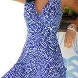 Woman wearing a blue and white geometric V-neck sleeveless A-line summer dress standing with her hand on her waist.