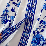 Blue and white porcelain print long sleeve floral dress with belt, featuring intricate patterns and a collared neckline.