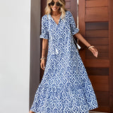 A woman wearing a blue and white V-neck boho maxi dress suitable for lightweight summer beachwear, accessorized with sunglasses.