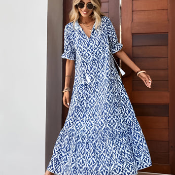 A woman wearing a blue and white V-neck boho maxi dress suitable for lightweight summer beachwear, accessorized with sunglasses.