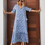 A woman wearing a blue and white V-neck boho maxi dress, suitable for lightweight summer beachwear, accessorized with sunglasses.