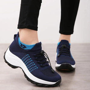 Blue women's athletic sneakers made of breathable mesh with a shock-absorbing sole, shown on a person's feet, highlighting their sporty design and electric blue color.
