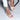 Blush pink low heel ballet flats with minimalist design, worn by a woman in a white dress, showing comfort and fashion.