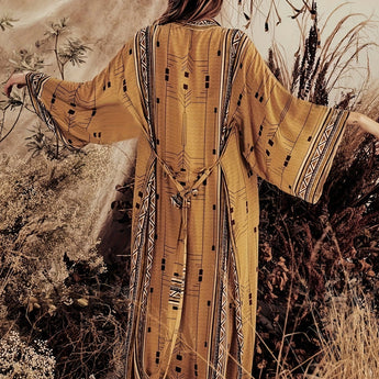 Bohemian beige kimono with boho-chic tribal pattern, worn by a person in a natural desert landscape, featuring long sleeves and an open front design.
