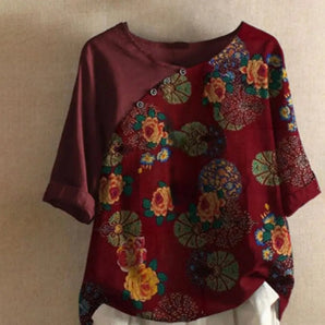 Bohemian burgundy blouse with floral embroidery, featuring an asymmetric design and a wine red color in XL size. The blouse has decorative accents on the neck and collar, with creative arts-inspired patterns including pink and magenta hues. The garment is made from natural materials with long sleeves.