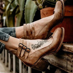 Rustic brown leather clogs with a bohemian style featuring double buckles and a unique tattoo design.