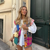 Bohemian embroidered patchwork dress in pink featuring intricate textile patterns, with the model standing and showcasing shoulder, sleeve, and waist details.