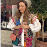 
A woman wearing a Bohemian embroidered patchwork dress with a smile, showcasing summer artisan fashion. The dress features intricate patterns and a blend of vibrant colors, highlighting its unique design.
