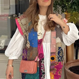 Bohemian embroidered patchwork dress featuring a mix of white and pink textiles with intricate designs. The dress showcases detailed embroidery on the shoulder and neck areas, with flowing sleeves and a fitted waist, embodying a chic and artisan summer fashion style.