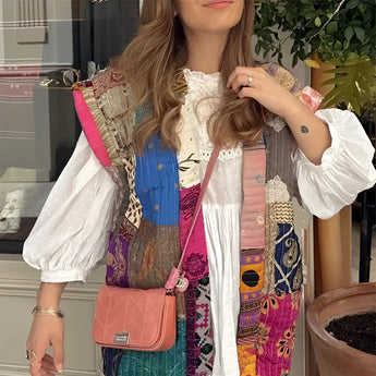 Bohemian embroidered patchwork dress featuring a mix of white and pink textiles with intricate designs. The dress showcases detailed embroidery on the shoulder and neck areas, with flowing sleeves and a fitted waist, embodying a chic and artisan summer fashion style.