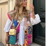 Bohemian embroidered patchwork dress featuring a colorful and intricate design, worn by a model accessorized with sunglasses, highlighting the dress's white and multicolored textile, short sleeves, and unique neckline.