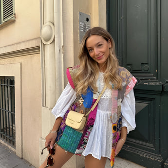 Bohemian embroidered patchwork dress featuring vibrant colors and intricate designs, modeled by a smiling woman with long hair, showcasing the dress's unique shoulder and neck detailing, perfect for summer fashion.